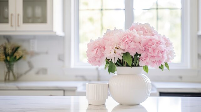 A white vase full of pink flowers is sitting on counter.