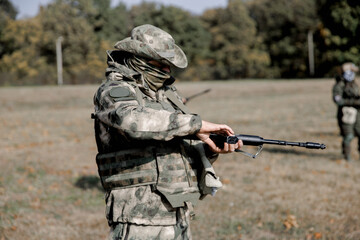 Fototapeta premium Soldiers in formation. Soldiers with a machine gun in military uniform. Special forces with weapons take part in a military maneuver. War, army, equipment and the concept of people. Camouflage. Traini