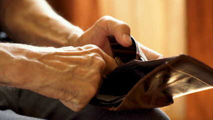 An elderly man's hands, covered with knotted veins, search for coins in his wallet - obrazy, fototapety, plakaty