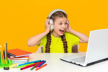 Online education. A little girl communicates with a teacher remotely using a laptop. A child with headphones is looking at a computer monitor.