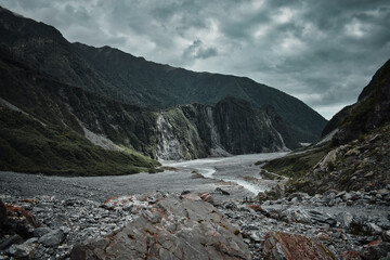 Fototapeta na wymiar Fox Glacier on the west coast of New Zealand winds through a long valley surrounded by imposing mountains and cliffs. Its grandeur and majesty are breathtaking. 