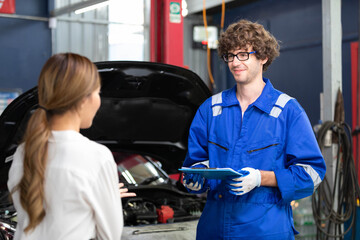 mechanic talking about how to fix a car to customer in automobile repair shop