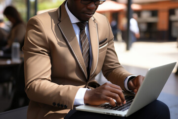 Young African American man in an elegant suit sits at a table in cafe with laptop computer. Positive successful businessman, entrepreneur, small business owner works online. Remote work concept.