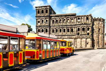 The city tour train at the Black Gate (Porta Nigra) stop, the historic city center of Trier,...