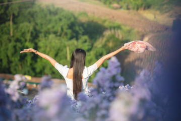 Rear view of beautiful woman standing with raised hands on lavender flower field.