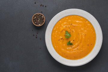 Pumpkin soup in bowl on black background with copy space. Cooking traditional seasonal food