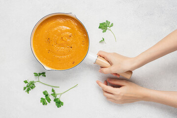 Female hands holding pumpkin soup in pan on white background with copy space. Cooking traditional...