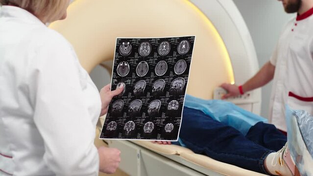 Medical hospital research laboratory: two doctors analyze MRI images of the brain after a CT scan. They are looking for treatment for the patient. Healthcare A neurologist treats people.