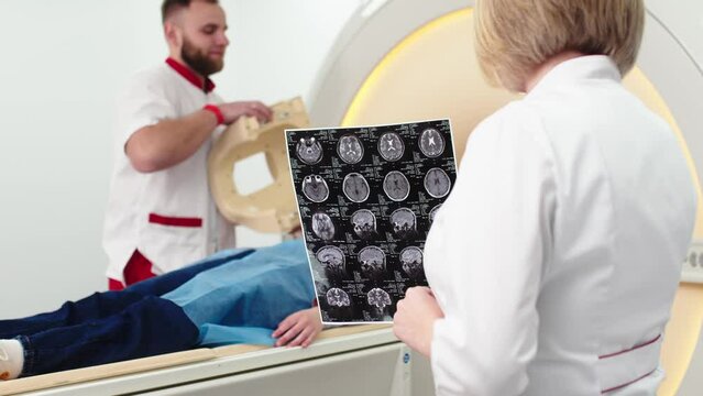 Medical hospital research laboratory: two doctors analyze MRI images of the brain after a CT scan. They are looking for treatment for the patient. Healthcare A neurologist treats people.