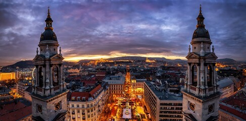 Obraz premium Panoramic view of the skyline of Budapest, Hungary, with a christmas market at the central square during a colorful winter sunset