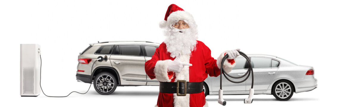 Santa claus with electric vehciles holding a charger at ev charging point
