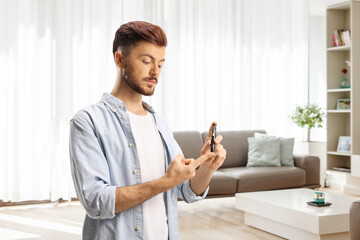 Guy poking finger with a lancet device at home