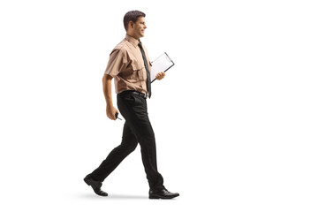 Full length profile shot of a security guard holding a clipboard and walking