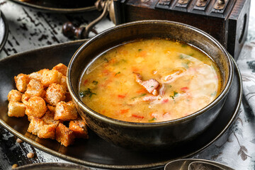 Vegetables soup with bacon, spices and croutons in bowl on rustic wooden background. Close up