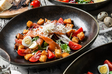 Healthy salmon salad with croutons, arugula, tomatoes, lettuce in plate on rustic wooden background. Healthy food, close up