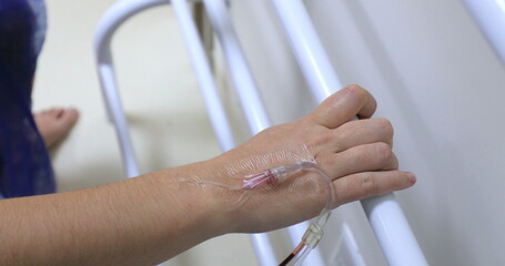 hand connected to IV drip at hospital holding on bar