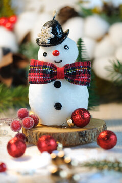 Snowman candle with tartar bow on Christmas background. Selective focus with shallow depth of field. Vertical image. Greeting card