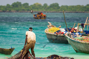African fisherman catches fishing nets and looks out to sea, sunny day , Zanzibar, tanzania.