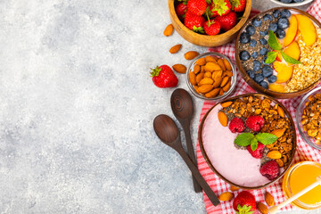 Fototapeta na wymiar Bowl of granola with yogurt and fresh berries on a texture table. Yogurt berries, acai bowl, spirulina bowl. Healthy food, balanced breakfast. Strawberries, blueberries, kiwi, peach, almonds and chia.