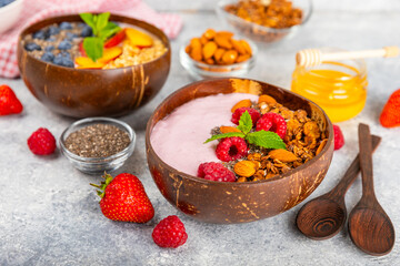Bowl of granola with yogurt and fresh berries on a texture table. Yogurt berries, acai bowl, spirulina bowl. Healthy food, balanced breakfast. Strawberries, blueberries, kiwi, peach, almonds and chia.