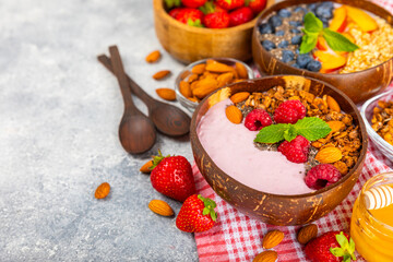 Bowl of granola with yogurt and fresh berries on a texture table. Yogurt berries, acai bowl, spirulina bowl. Healthy food, balanced breakfast. Strawberries, blueberries, kiwi, peach, almonds and chia.