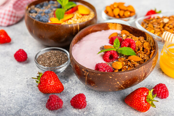 Bowl of granola with yogurt and fresh berries on a texture table. Yogurt berries, acai bowl, spirulina bowl. Healthy food, balanced breakfast. Strawberries, blueberries, kiwi, peach, almonds and chia.