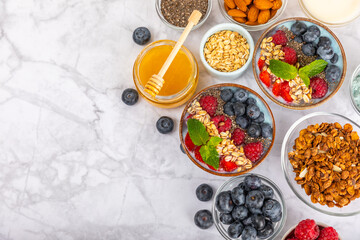 Bowl of granola with yogurt and fresh berries on a texture table. Yogurt berries, acai bowl, spirulina bowl. Healthy food, balanced breakfast. Strawberries, blueberries, kiwi, peach, almonds and chia.