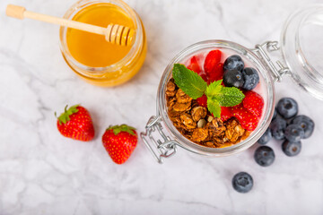 Bowl of granola with yogurt and fresh berries on a texture table. Yogurt berries, acai bowl, spirulina bowl. Healthy food, balanced breakfast. Strawberries, blueberries, kiwi, peach, almonds and chia.