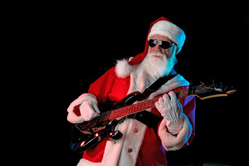 Santa Claus playing the electric guitar in a nightclub at a Christmas and New Year party or...