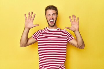 Young Caucasian man on a yellow studio background receiving a pleasant surprise, excited and...