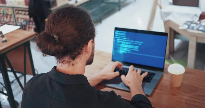 programmer analyzing data. A male programmer involved in software development or analyzing data.. IT specialist have a working day male sitting back view in cafe and analyzing data in your laptop