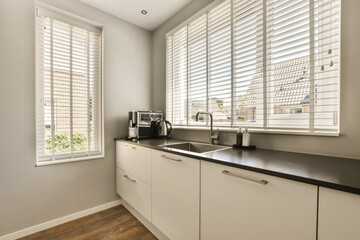 a kitchen area with white cabinets and black counter tops in front of the window that looks out...
