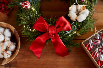 winter holidays, diy and hobby concept - close up of christmas fir wreath and decorations on wooden table