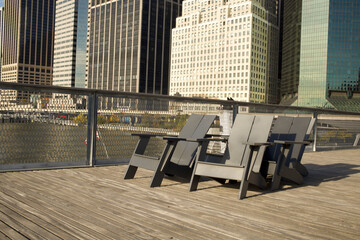 Empty deck chairs on Pier 15 with skyscrapers of Manhattans Financial District in the background