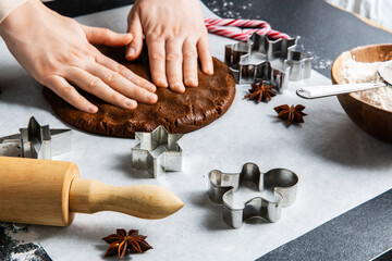 baking, cooking and christmas concept - close up of hands spreading gingerbread dough on black...