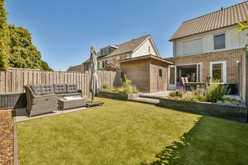 a backyard area with lawn, couch and fenced in the back yard on a clear blue sky day stock photo