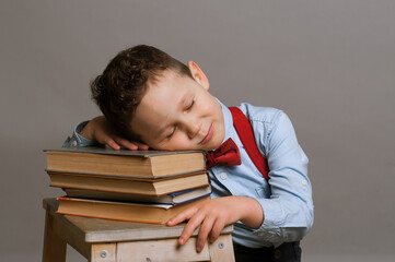 Sleeping elementary aged boy sitting at the desk with books