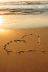 A heart is drawn on the sand on the beach at sunset. Romantic sunset on the beach. Heart shape....