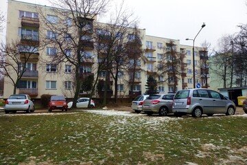 Housing estate with low-rise apartment blocks with cars parked by the road - lawn under snow , thaw , begins spring