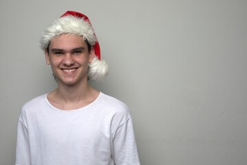 Handsome happy teenager boy young man in Santa Claus hat smiling widely
