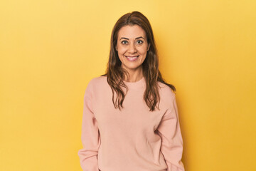 Obraz premium Cheerful middle aged woman posing on a yellow backdrop