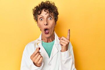 Doctor with invisible dental aligner on yellow having some great idea, concept of creativity.