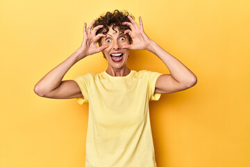 Mid-aged caucasian woman on vibrant yellow keeping eyes opened to find a success opportunity.