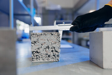 Worker engineer measures and controls quality of concrete cube in laboratory. Concept industry lab...