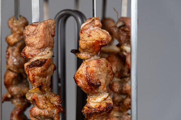 Cooking pork meat in an electric kebab maker on vertical skewers