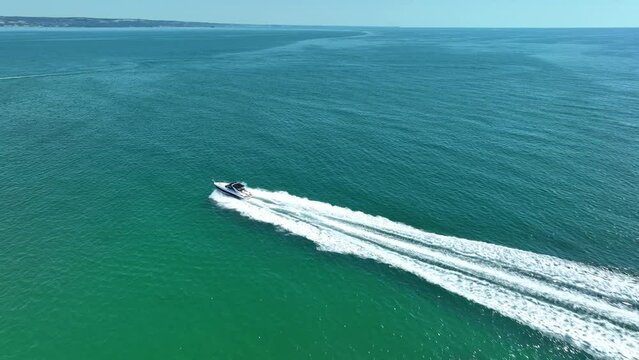 Drone view of a  Luxury boat the blue clear waters. Top view of a fast movement  white boat sailing to the blue sea. Large speed boat moving at high speed. Summer image.