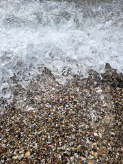 Wave rolling over colorful pebbles on a beach - 664584390