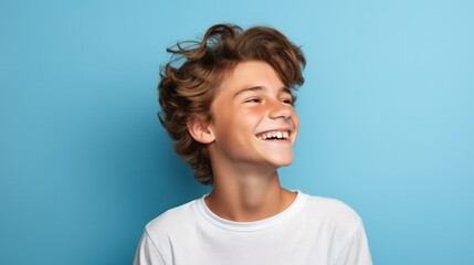 A cheerful teenage boy, isolated on a blue background, exuding youthful exuberance, showcasing moments of joy.