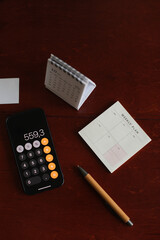 Flatlay of calculator on mobile phone, pen, calendar, planner, notepad on table background. Aesthetic home office desk workspace. business, work, blog template with mockup space. Flat lay, top view