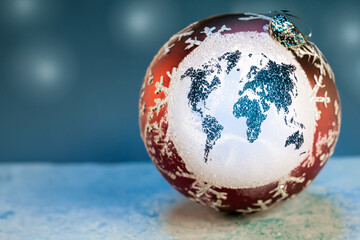 Christmas sphere with a figure of the world map in glitter on snow with space for text.